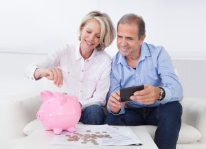 Happy Mature Couple Calculating Coin In The Piggybank